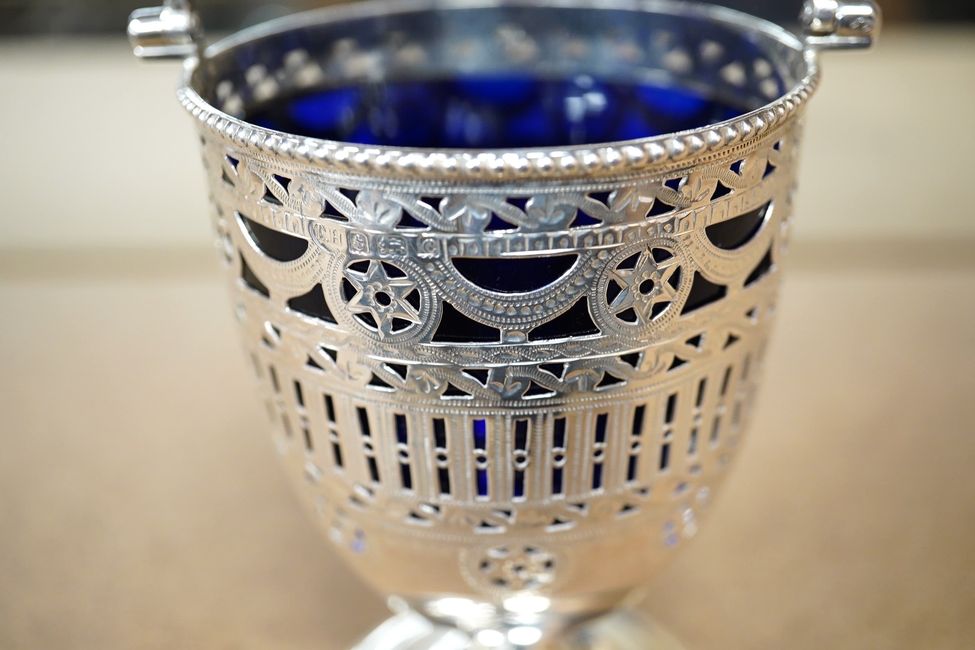 An Edwardian pierced silver pedestal sugar basket, with later? blue glass liner, Thomas Hayes, Birmingham, 1904, 11.7cm. Condition - fair to good